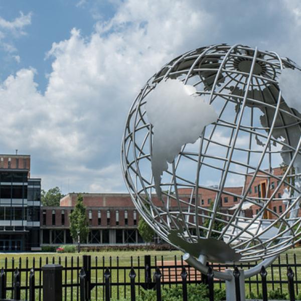 The globe sculpture on the campus green with the Ely Campus Center in the background