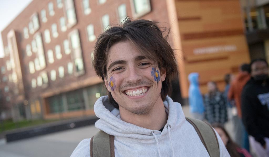 Smiling student with painted flowers on his cheeks